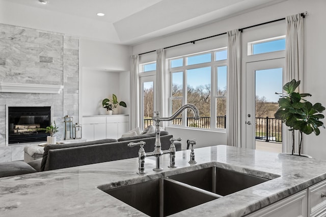 kitchen featuring a sink, a wealth of natural light, light stone countertops, and open floor plan