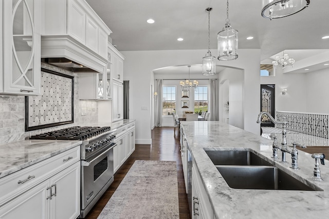 kitchen with an inviting chandelier, arched walkways, tasteful backsplash, a sink, and stainless steel range