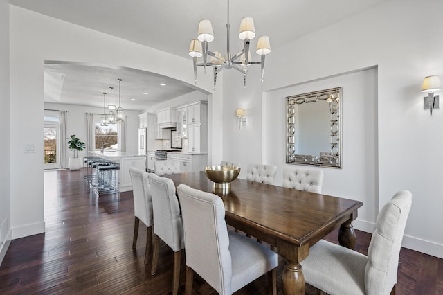 dining area featuring an inviting chandelier, baseboards, dark wood-type flooring, recessed lighting, and arched walkways