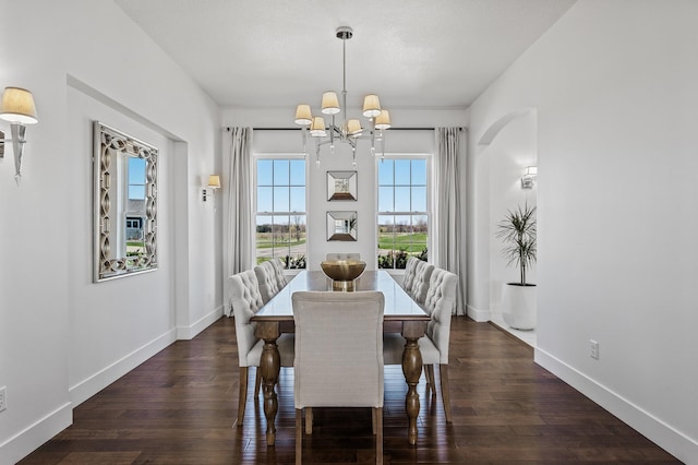 dining space featuring wood-type flooring, baseboards, and an inviting chandelier