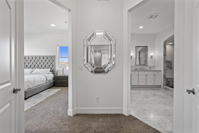 corridor with visible vents, carpet floors, baseboards, recessed lighting, and a sink