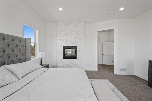 bedroom with a stone fireplace, visible vents, baseboards, carpet flooring, and recessed lighting