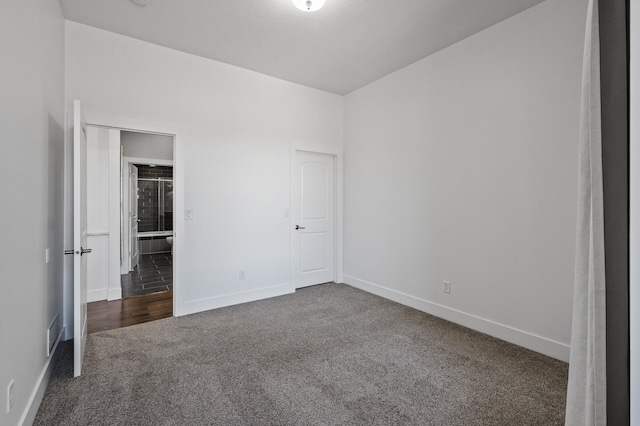 unfurnished bedroom with baseboards, dark carpet, and visible vents