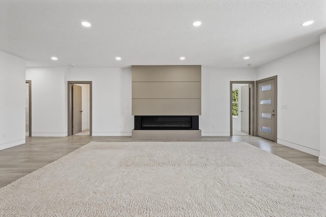 unfurnished living room featuring recessed lighting, light wood-style flooring, baseboards, and a fireplace