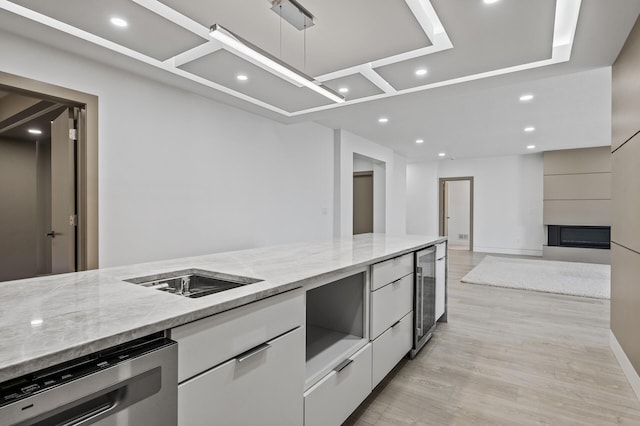 kitchen with light stone countertops, beverage cooler, modern cabinets, white cabinets, and dishwasher