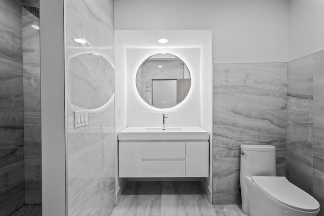 bathroom with toilet, tile walls, marble finish floor, and vanity