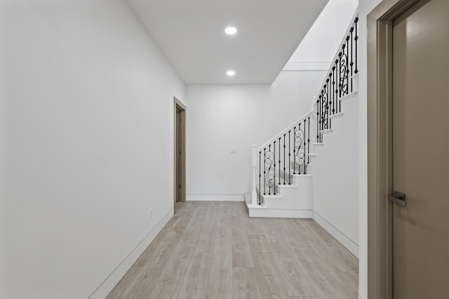 hallway featuring recessed lighting, baseboards, light wood finished floors, and stairs
