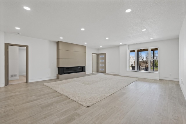 unfurnished living room featuring recessed lighting, baseboards, and light wood-type flooring