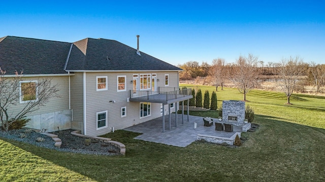 rear view of property with a patio, a shingled roof, an outdoor stone fireplace, and a yard