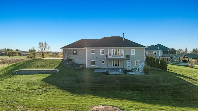back of property with a lawn, a patio area, and a balcony