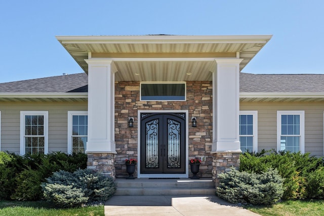 entrance to property with roof with shingles and stone siding