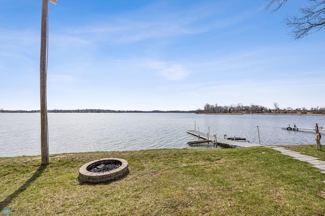 view of dock featuring a water view, an outdoor fire pit, and a yard