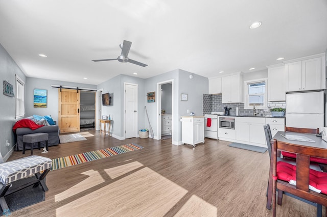 kitchen featuring white appliances, baseboards, open floor plan, a barn door, and a sink