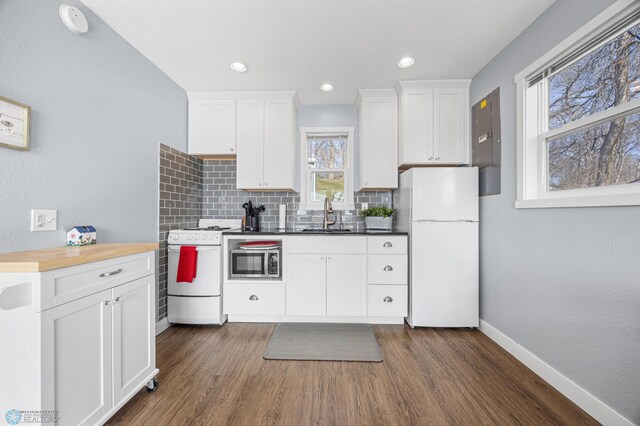 kitchen featuring white appliances, dark wood-style flooring, a sink, and tasteful backsplash