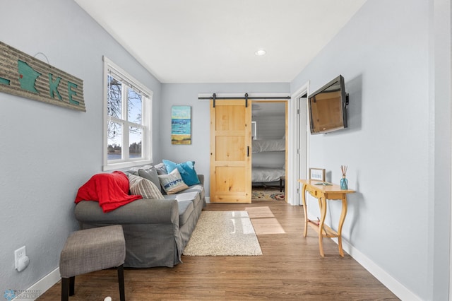 living area featuring baseboards, a barn door, wood finished floors, and recessed lighting