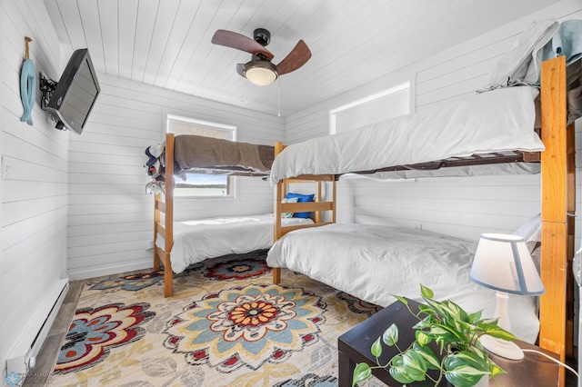 bedroom featuring wooden walls, baseboard heating, a ceiling fan, and wood ceiling
