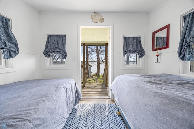bedroom featuring access to outside, ornamental molding, and wood finished floors