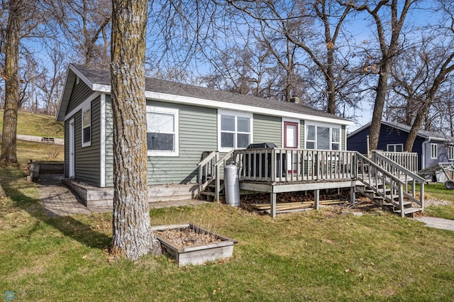 view of front of house with a shingled roof, a wooden deck, a chimney, and a front lawn