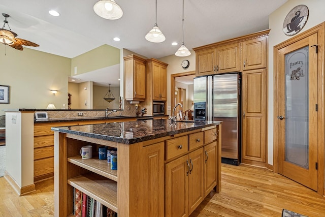 3041 209th Ln NW, Oak Grove, MN 55011 - kitchen with appliances with stainless steel finishes, open shelves, light wood-style flooring, a center island with sink, and a ceiling fan