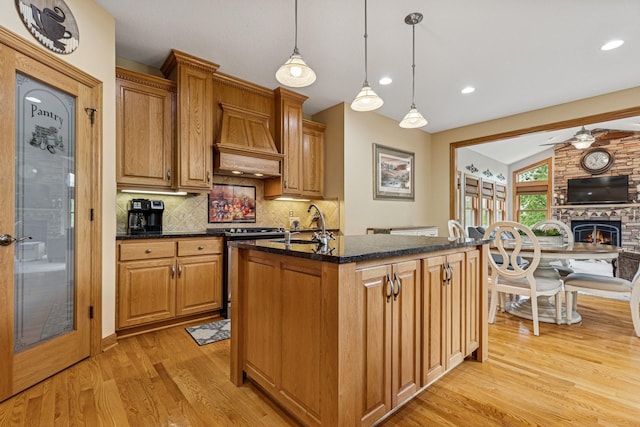 3041 209th Ln NW, Oak Grove, MN 55011 - kitchen featuring light wood-type flooring, backsplash, a brick fireplace, dark stone counters, and ceiling fan