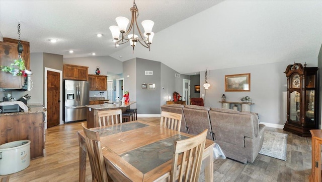 dining area featuring an inviting chandelier, visible vents, baseboards, light wood finished floors, and vaulted ceiling