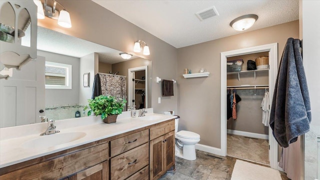 bathroom with a sink, toilet, double vanity, and visible vents