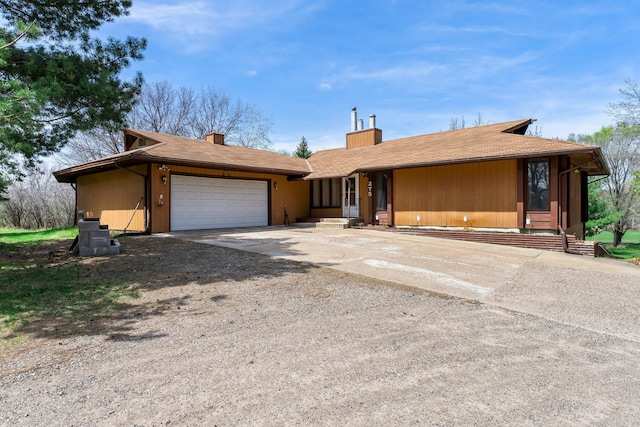 single story home featuring concrete driveway, an attached garage, and a chimney