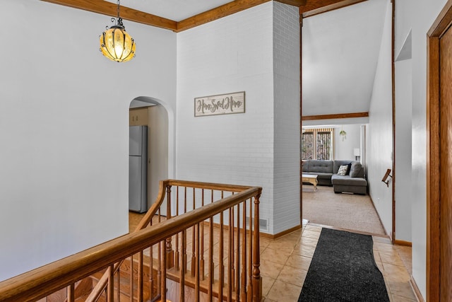 hall with beam ceiling, arched walkways, baseboards, light tile patterned floors, and a towering ceiling