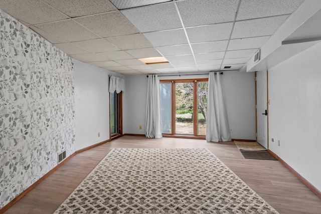 spare room with visible vents, baseboards, a drop ceiling, and wood finished floors