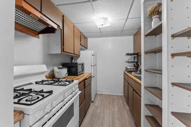 kitchen with white appliances, light countertops, a paneled ceiling, light wood-type flooring, and under cabinet range hood
