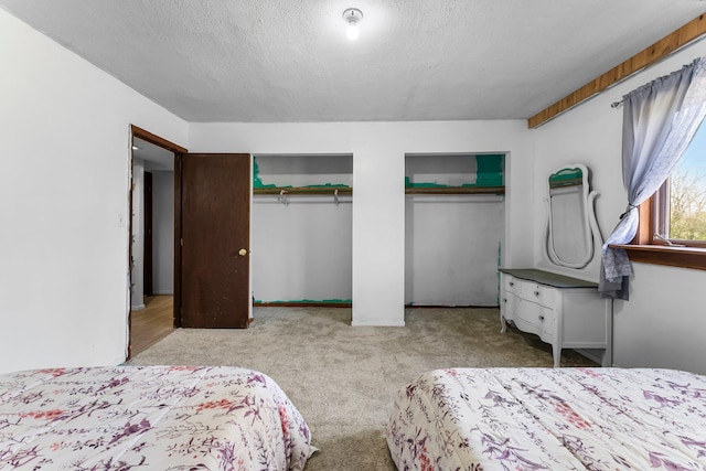 bedroom featuring two closets, a textured ceiling, and carpet floors