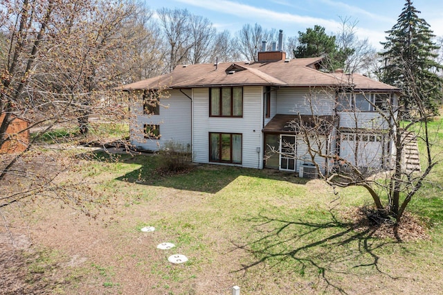 back of property featuring a yard, a chimney, and a shingled roof