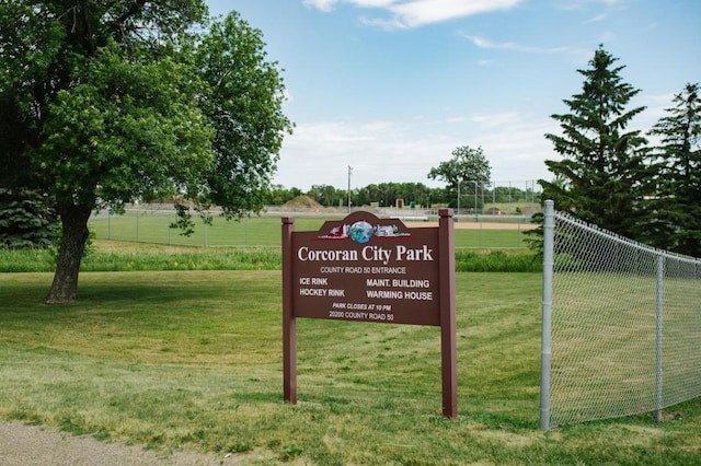 community / neighborhood sign featuring fence and a yard