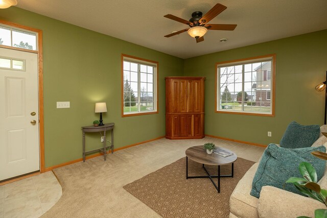 living area featuring baseboards, a healthy amount of sunlight, and carpet flooring