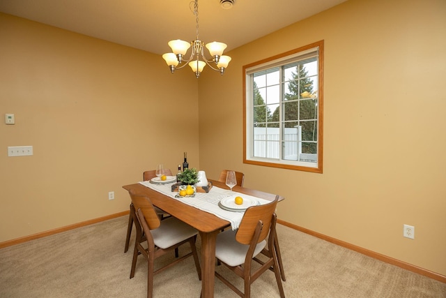 dining space with a chandelier, baseboards, and light carpet