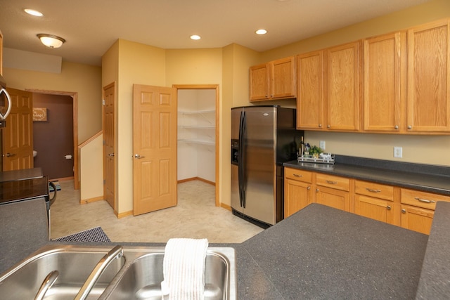 kitchen with dark countertops, recessed lighting, a sink, and stainless steel fridge with ice dispenser