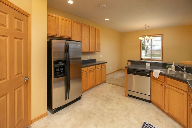 kitchen featuring dark countertops, stainless steel appliances, a notable chandelier, and a sink