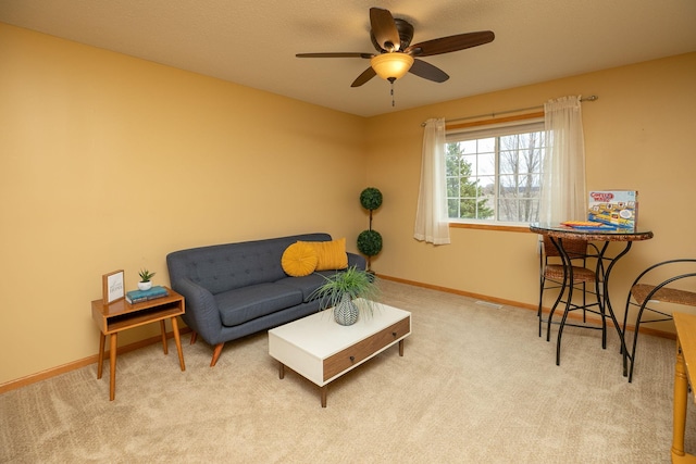 living area with baseboards, ceiling fan, and carpet