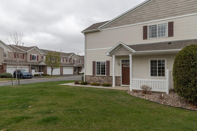 view of front of house featuring a shingled roof, a front lawn, and a residential view