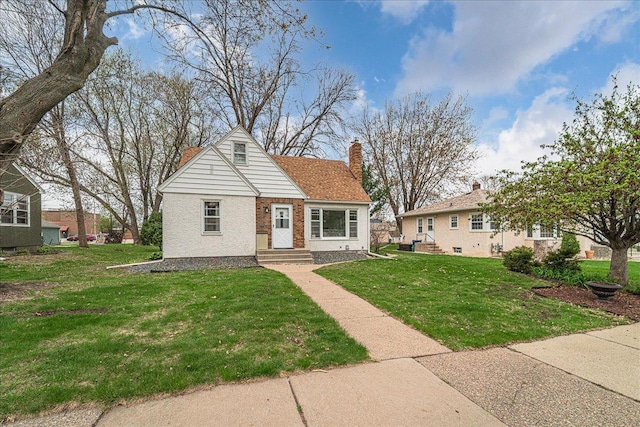 bungalow featuring brick siding, a chimney, and a front yard