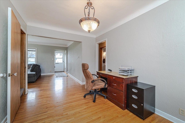 office area with baseboards, light wood finished floors, and a textured wall