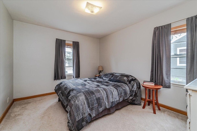 bedroom featuring baseboards, multiple windows, and light colored carpet