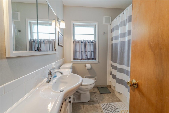 bathroom featuring tile patterned flooring, a healthy amount of sunlight, toilet, and vanity