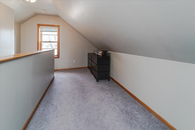 additional living space with light colored carpet, baseboards, and vaulted ceiling