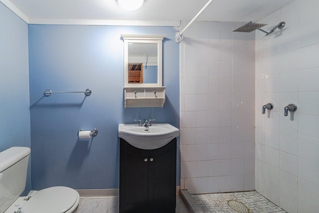 bathroom featuring vanity, baseboards, a tile shower, and toilet