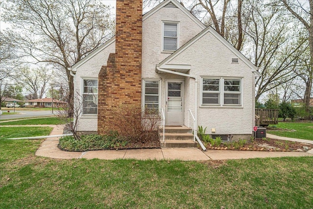 view of front of property featuring central AC, a chimney, and a front yard