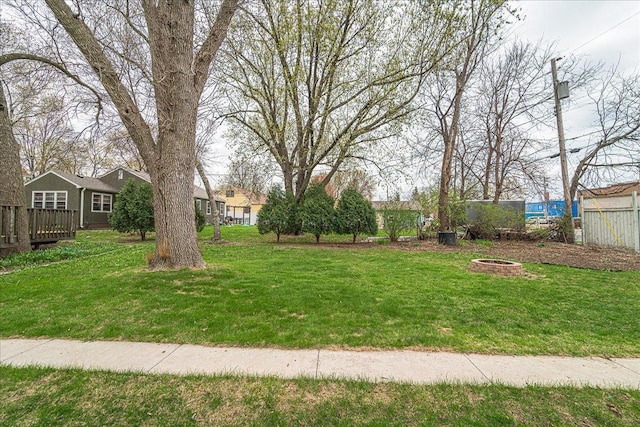 view of yard with a deck, fence, and a fire pit
