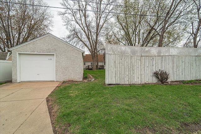 view of yard featuring concrete driveway, fence, an outbuilding, and a garage