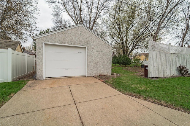 detached garage featuring fence and concrete driveway