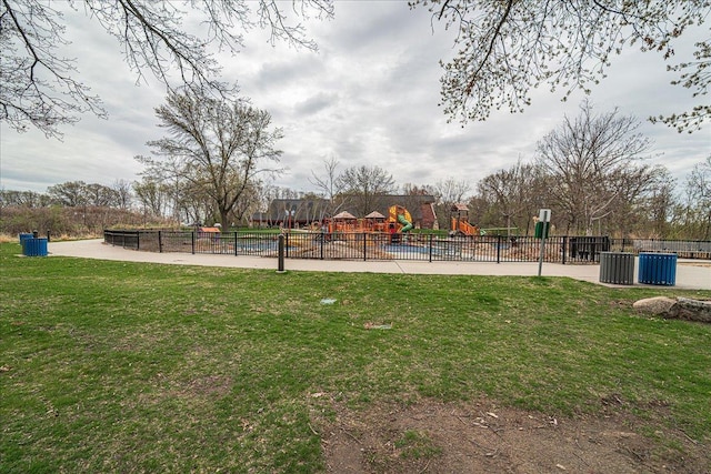 view of property's community with a playground, fence, and a yard